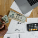 man counting money at a table with a calculator nearby: Can I Afford a Financial Advisor?
